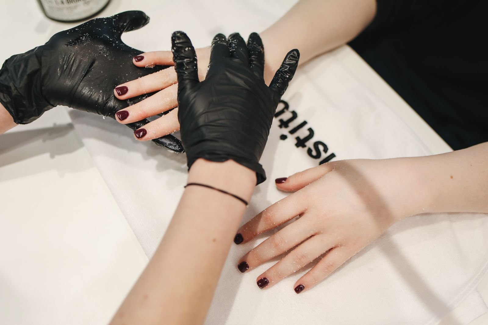 Technician applying top coat during a milky chrome manicure session