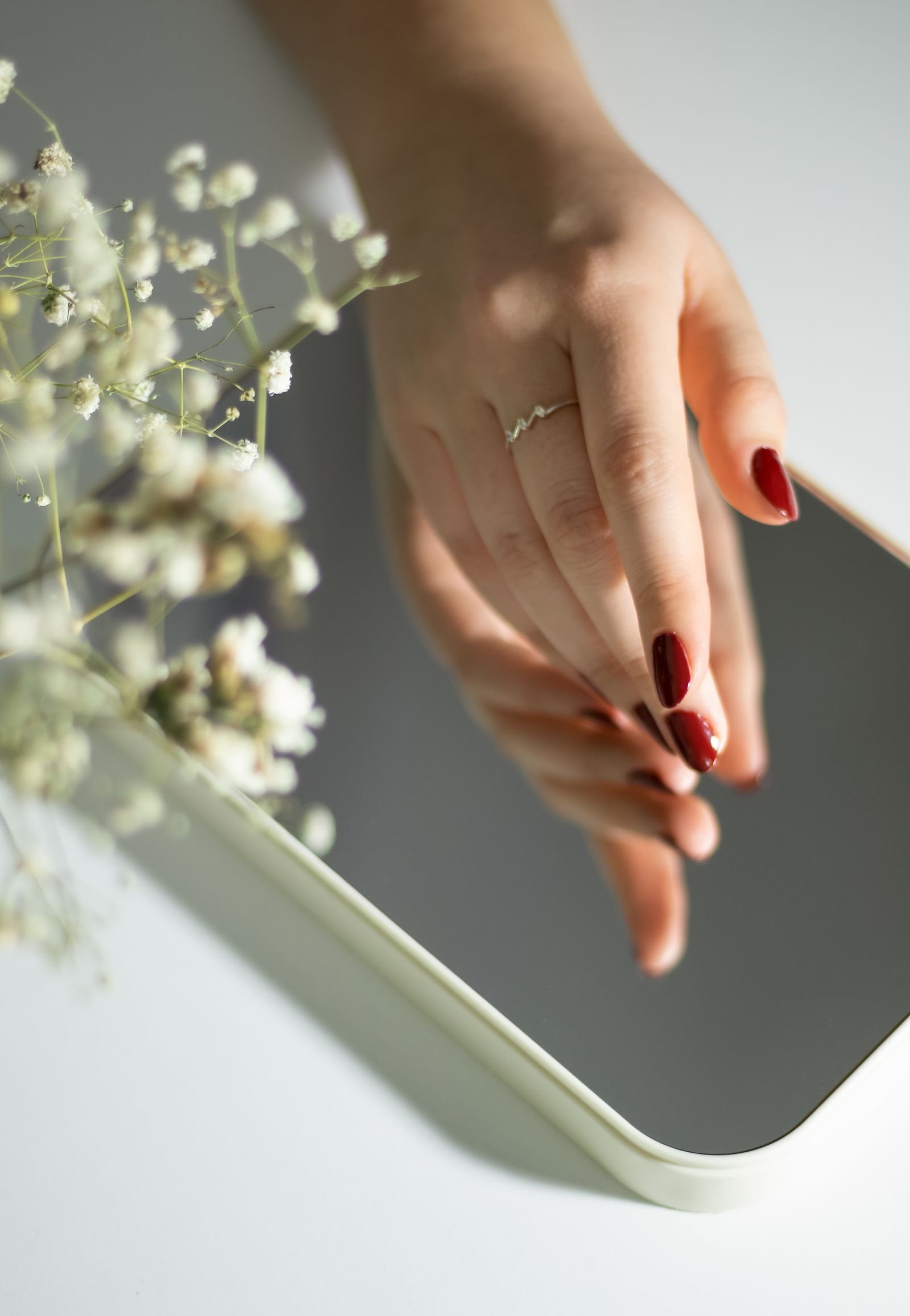 Graceful hand with milky chrome nails and a ring in soft light