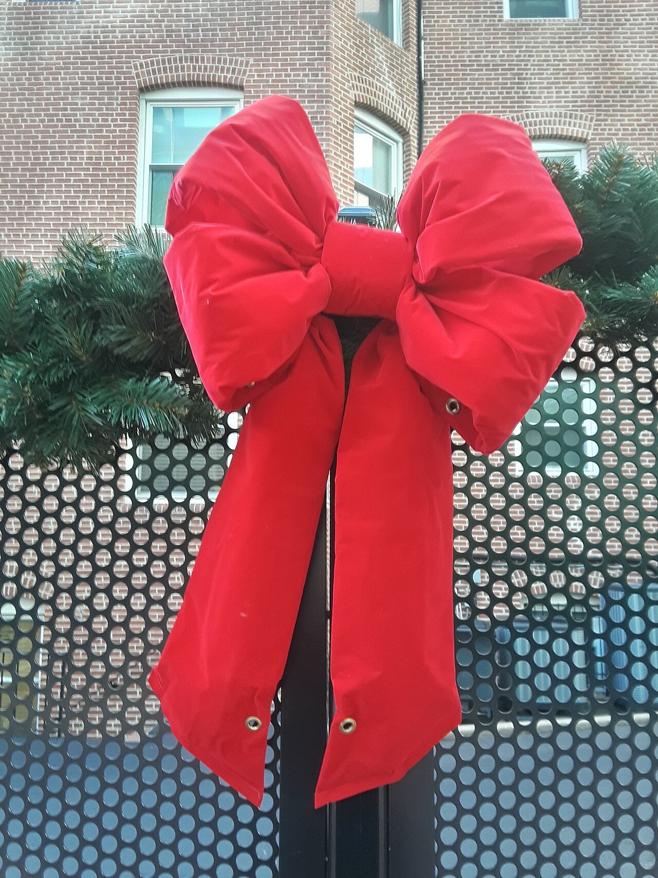 Large red velvet bow tied on Christmas greenery
