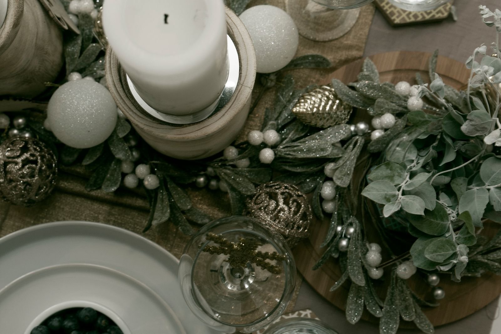 Candlelit holiday table with ornaments and greenery in warm light
