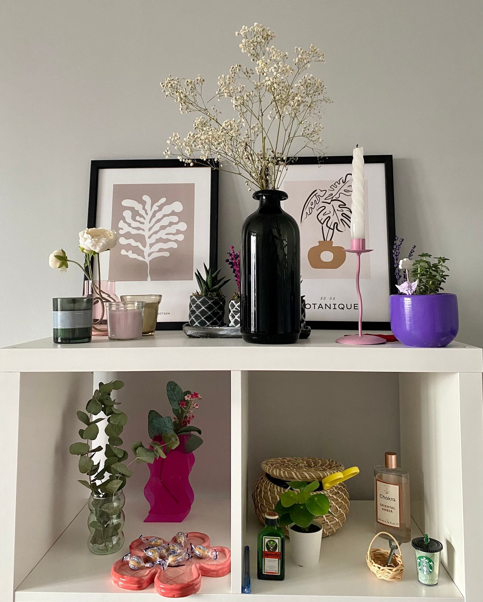 Stylish shelf styled with vases, plants and framed botanical prints